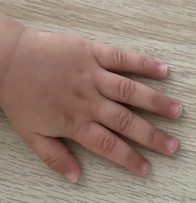 Une main d'enfant posée à plat sur une surface claire, vue de dessus, doigts légèrement écartés.